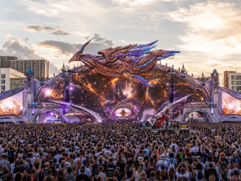 Large fantasy-inspired festival stage with a giant dragon installation and a dense audience