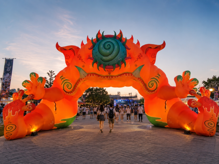Large inflatable monster entrance arch illuminated at an outdoor festival